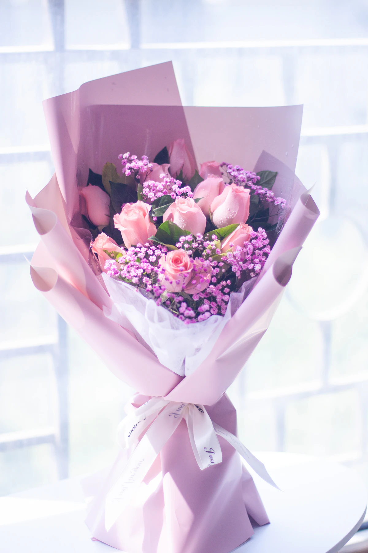 A bouquet of pink roses wrapped in soft pink paper