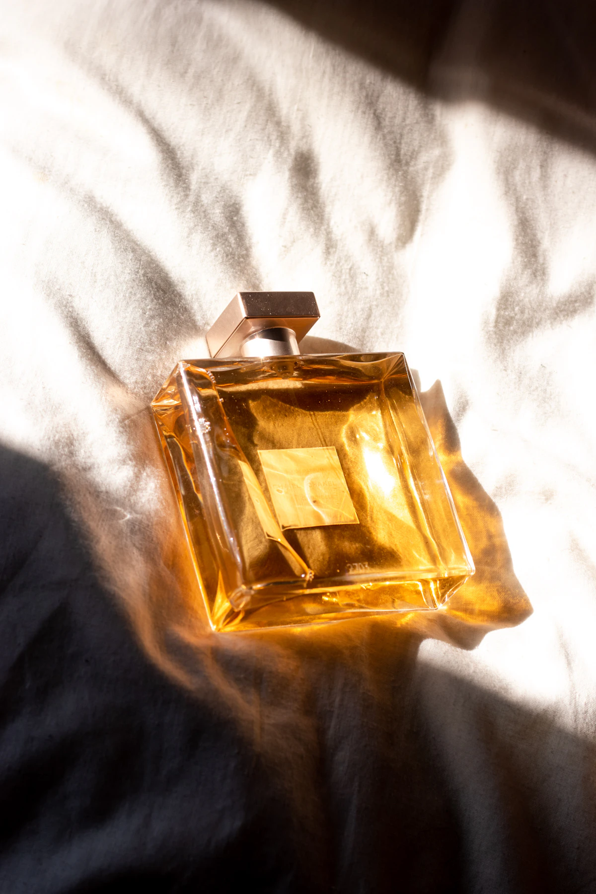 A gold perfume bottle resting on white fabric